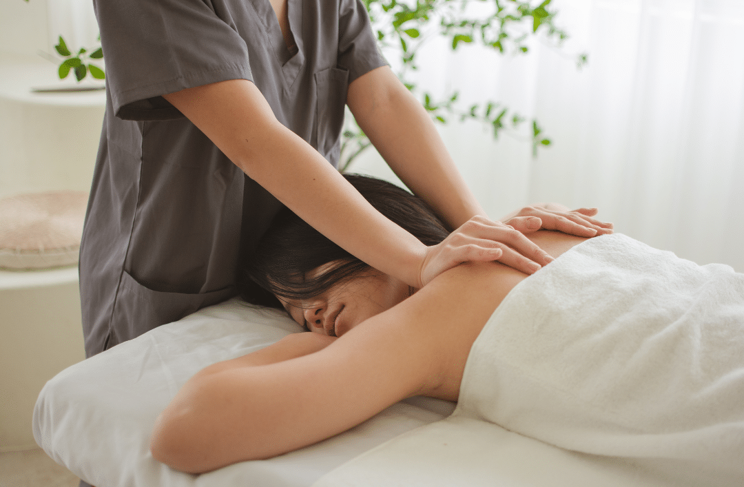 Massage therapist using both hands to apply pressure on a patient's upper back
