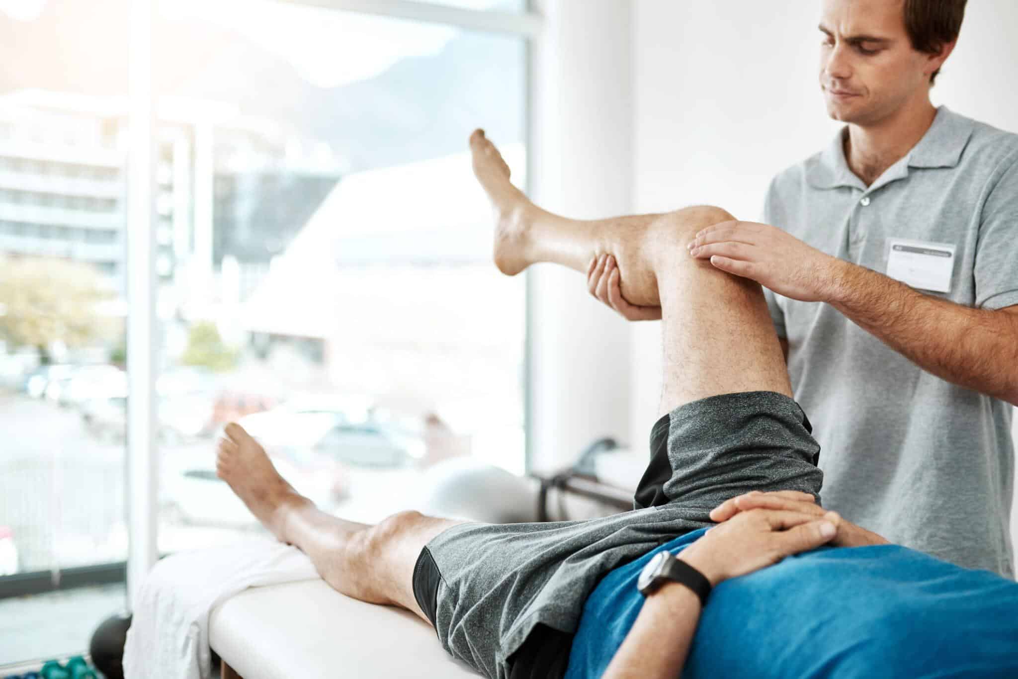 Therapist supporting a patient's bent knee during rehabilitation