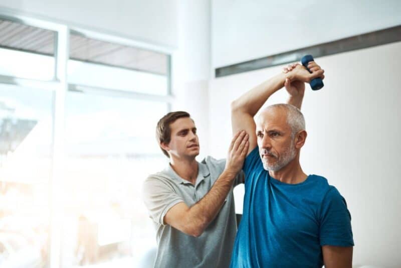 Shot of a young male physiotherapist helping a client with stretching exercises in his office during the day
